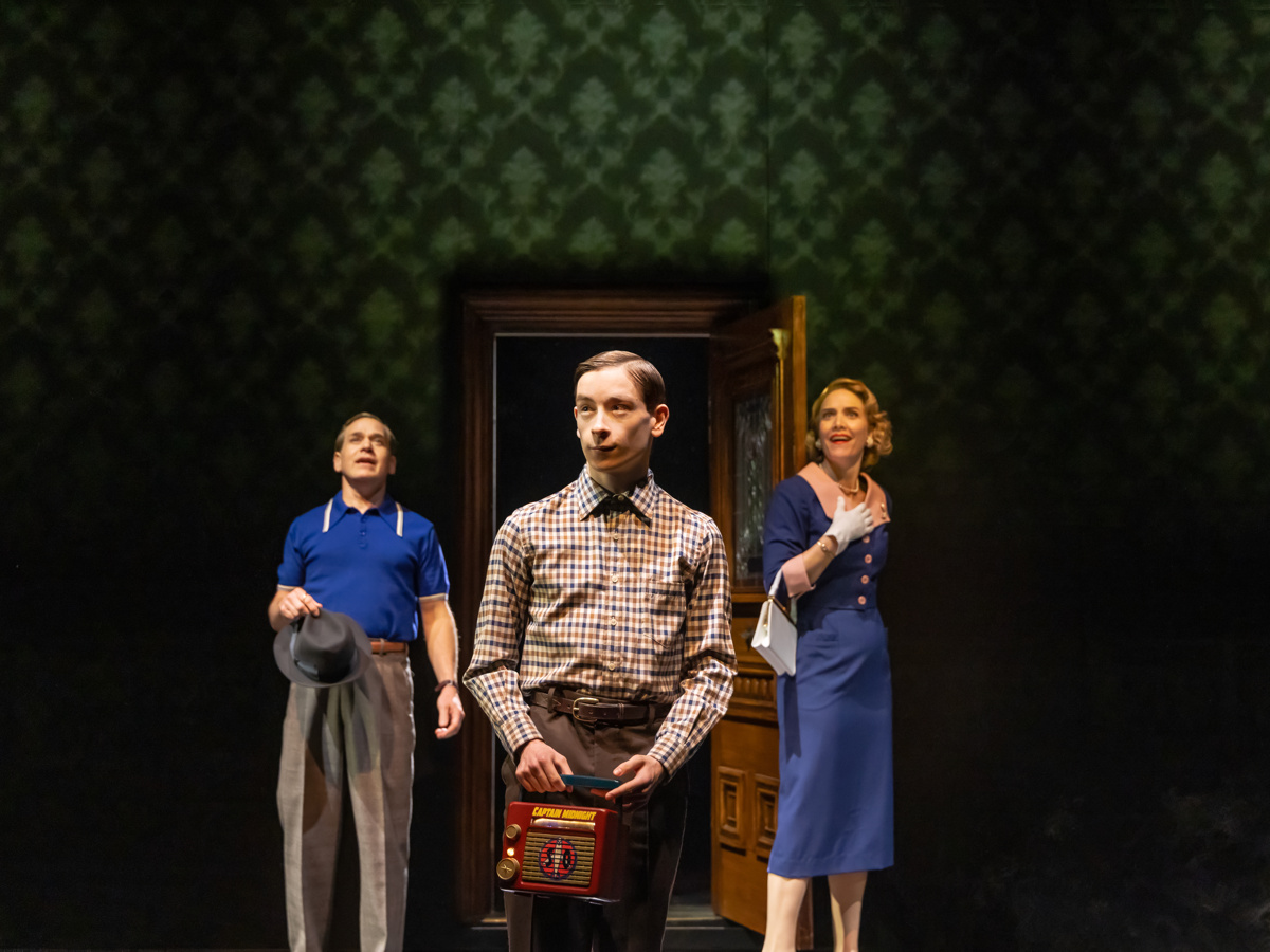 T.R. Knight, Louis McCartney and Rosie Benton stand in the center of a living room in Stranger Things: The First Shadow on Broadway